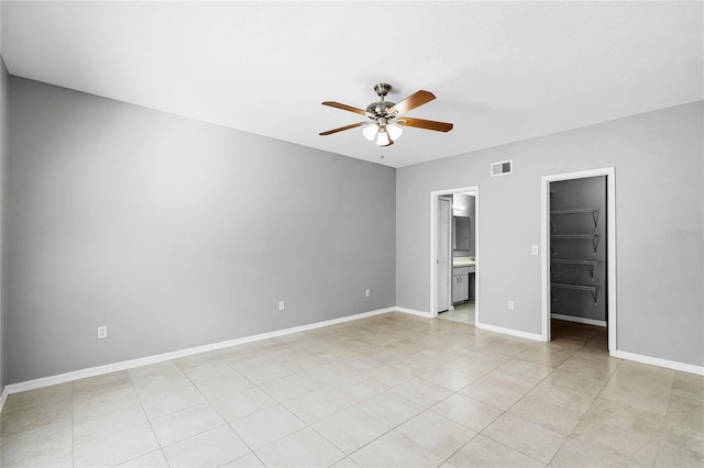 unfurnished bedroom featuring a walk in closet, ensuite bath, ceiling fan, light tile patterned floors, and a closet