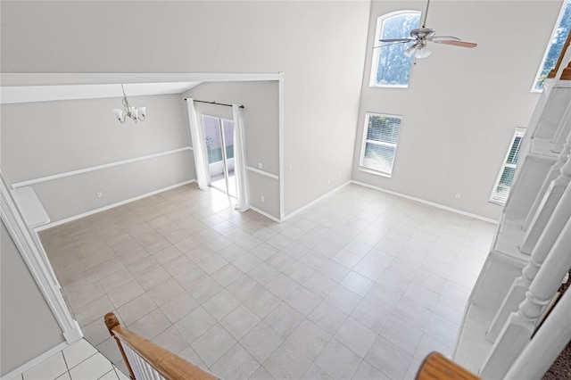 unfurnished living room with ceiling fan with notable chandelier, lofted ceiling, and light tile patterned floors