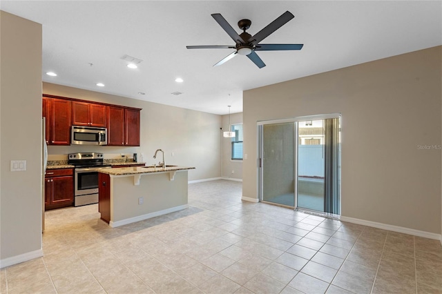 kitchen with a kitchen island with sink, a kitchen breakfast bar, sink, ceiling fan, and appliances with stainless steel finishes