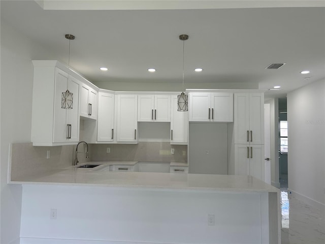 kitchen with tasteful backsplash, visible vents, a peninsula, white cabinets, and marble finish floor