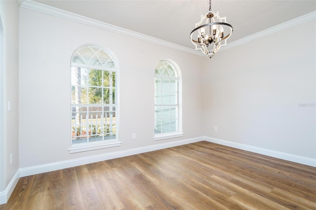 spare room featuring hardwood / wood-style floors, crown molding, and a chandelier