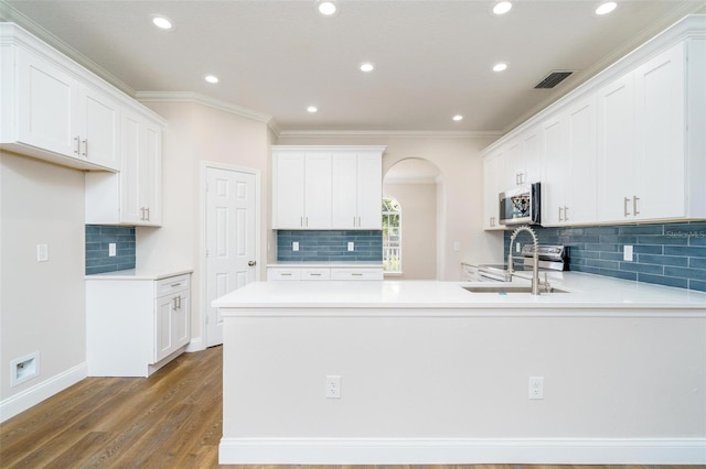 kitchen featuring dark hardwood / wood-style flooring, ornamental molding, stainless steel appliances, sink, and white cabinets