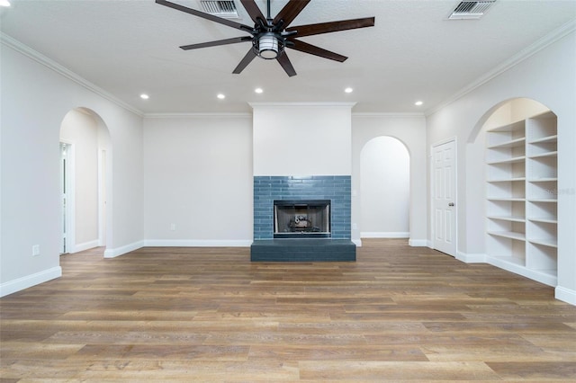 unfurnished living room featuring a fireplace, wood-type flooring, ceiling fan, and ornamental molding