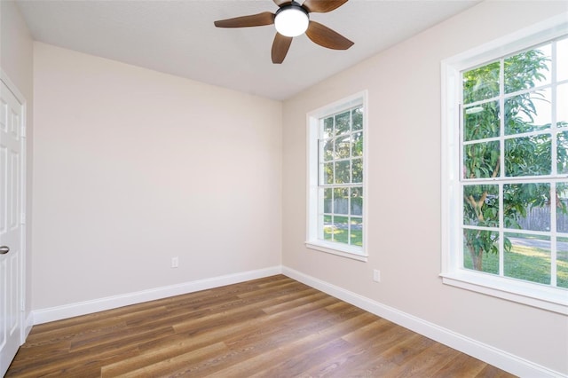 spare room featuring plenty of natural light, dark wood-type flooring, and ceiling fan