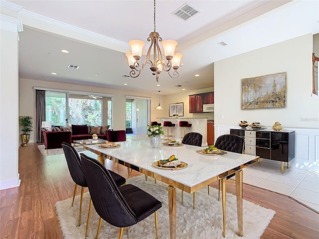 dining room with light hardwood / wood-style flooring, ornamental molding, and a notable chandelier