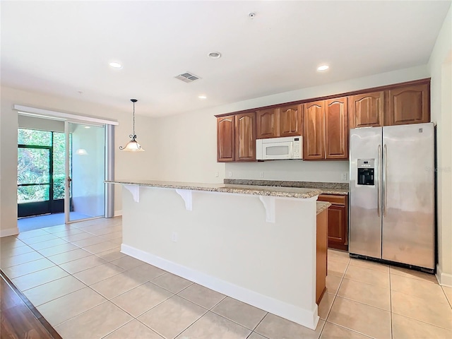 kitchen featuring a center island, hanging light fixtures, stainless steel fridge with ice dispenser, light stone counters, and a breakfast bar