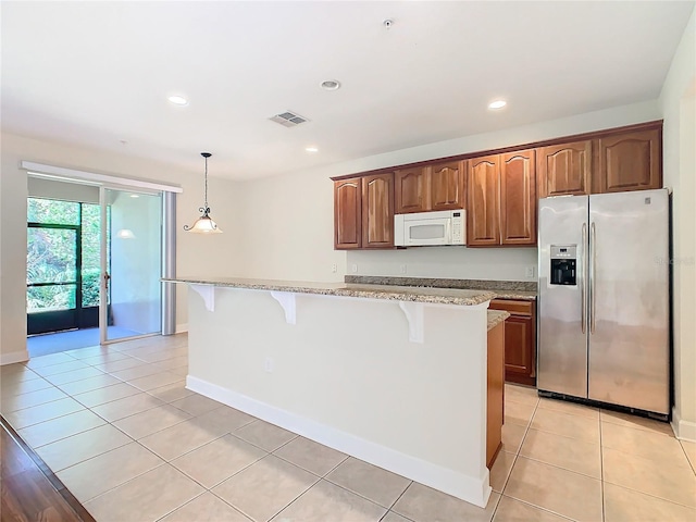 1300 Gilford Point Ln Unit 1300, Davenport, FL 33896 - kitchen with white microwave, stainless steel fridge, a kitchen bar, light stone counters, and a center island