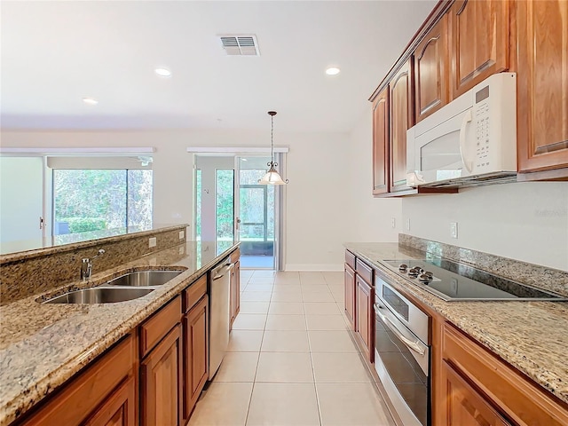 kitchen with sink, light tile patterned floors, decorative light fixtures, light stone counters, and stainless steel appliances