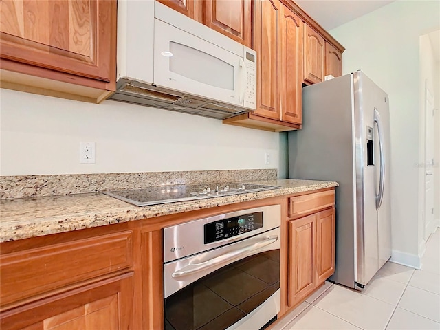 kitchen with light stone counters, light tile patterned floors, and stainless steel appliances