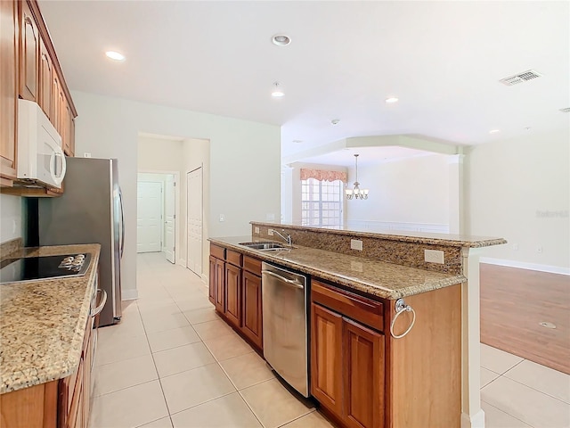 1300 Gilford Point Ln Unit 1300, Davenport, FL 33896 - kitchen with stainless steel appliances, light tile patterned floors, a chandelier, a kitchen island with sink, and brown cabinetry