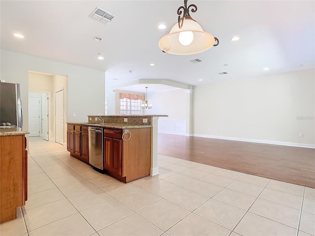 kitchen with light stone countertops, appliances with stainless steel finishes, decorative light fixtures, an inviting chandelier, and light tile patterned flooring