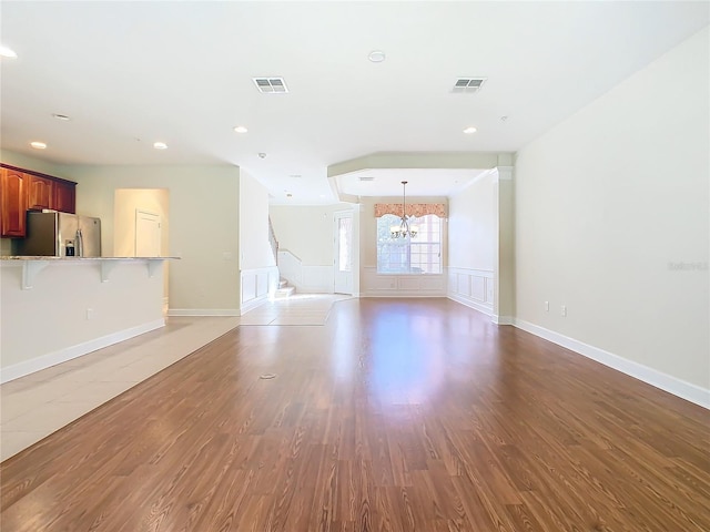 1300 Gilford Point Ln Unit 1300, Davenport, FL 33896 - unfurnished living room featuring a chandelier, light wood-style floors, recessed lighting, a wainscoted wall, and stairs