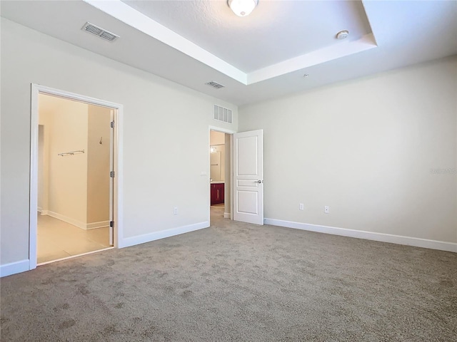 unfurnished bedroom featuring a raised ceiling and carpet floors