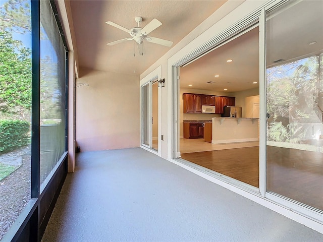 unfurnished sunroom featuring ceiling fan