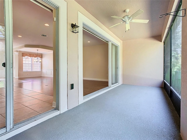 unfurnished sunroom with ceiling fan with notable chandelier