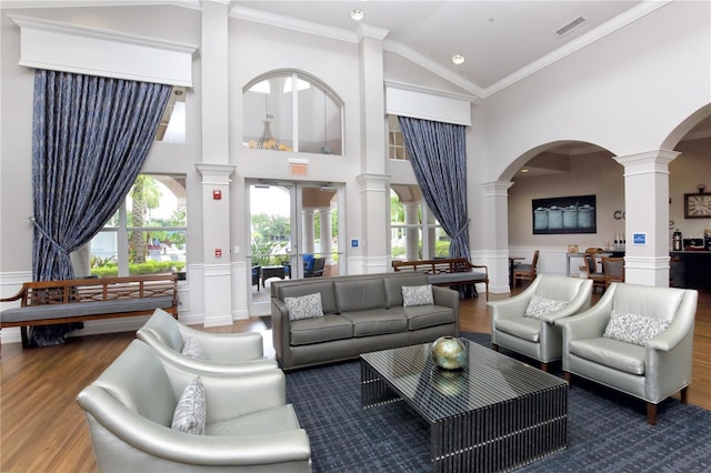 living room featuring a wealth of natural light, high vaulted ceiling, ornamental molding, and hardwood / wood-style flooring