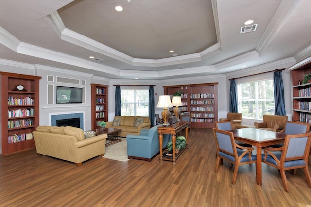 living room featuring hardwood / wood-style floors, a raised ceiling, a wealth of natural light, and crown molding