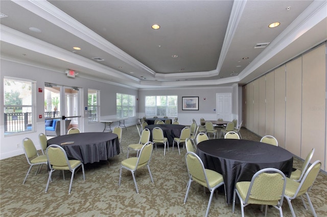 carpeted dining room featuring a raised ceiling, ornamental molding, and a wealth of natural light