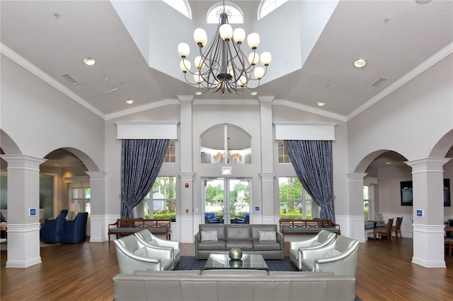 living room featuring dark hardwood / wood-style floors, plenty of natural light, ornamental molding, and an inviting chandelier