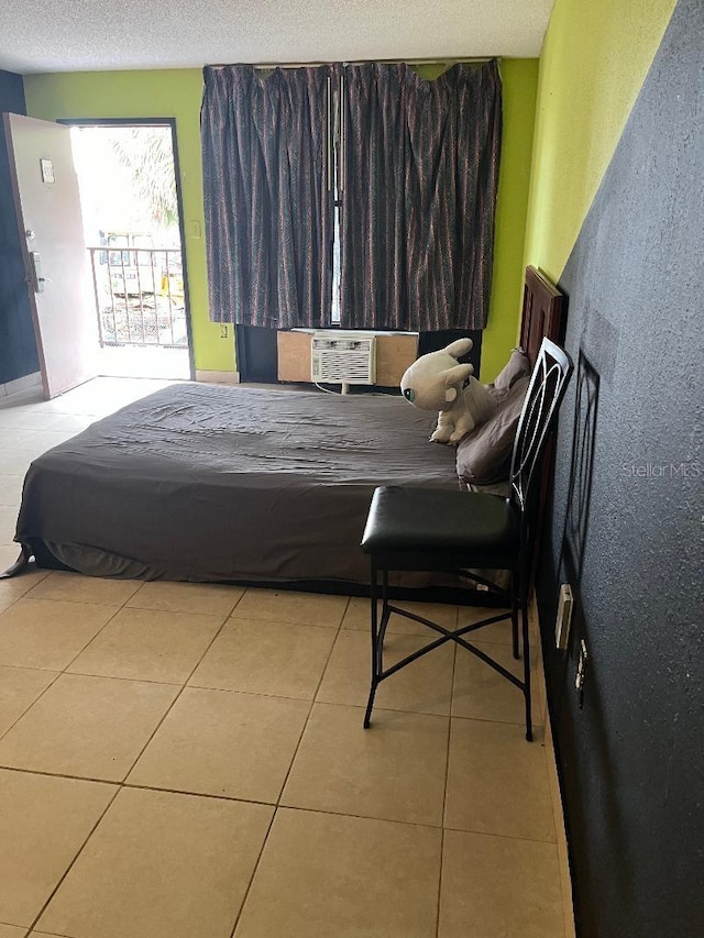 bedroom featuring cooling unit, light tile patterned floors, and a textured ceiling