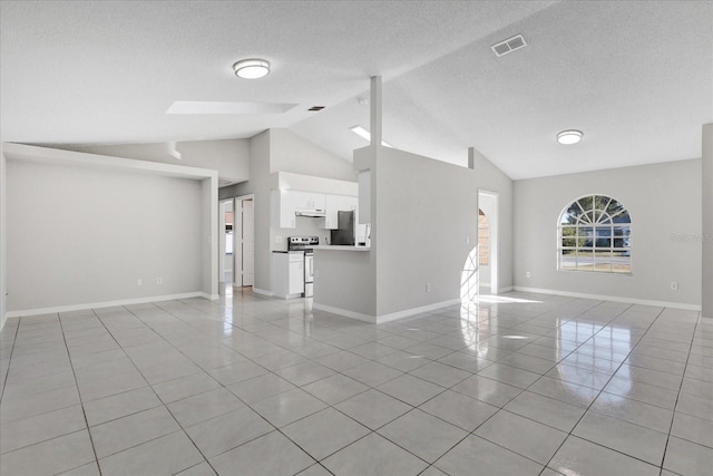 unfurnished living room with light tile patterned floors, lofted ceiling with skylight, and a textured ceiling