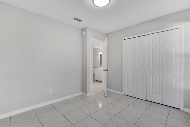 unfurnished bedroom featuring light tile patterned floors, a closet, and a textured ceiling