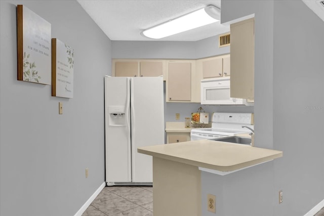 kitchen featuring kitchen peninsula, a kitchen bar, white appliances, cream cabinetry, and light tile patterned flooring