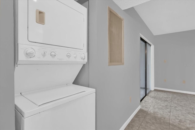 clothes washing area featuring tile patterned flooring and stacked washer and dryer