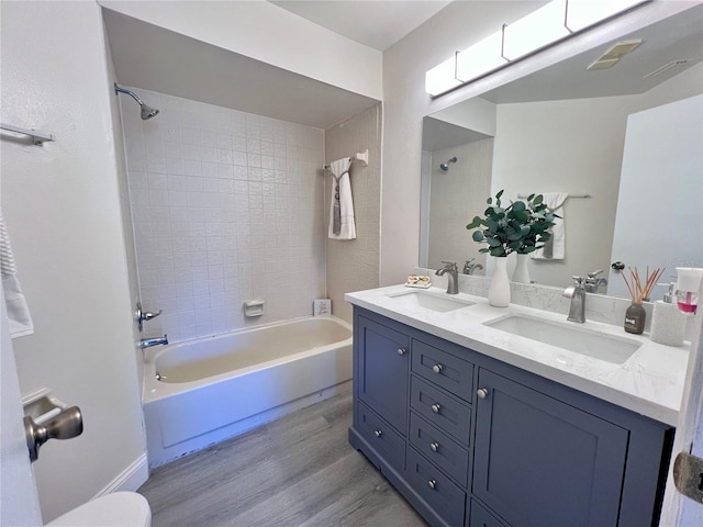 bathroom with vanity, wood-type flooring, and tiled shower / bath combo