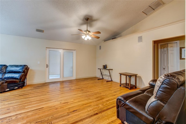 living area with a textured ceiling, ceiling fan, light hardwood / wood-style floors, and vaulted ceiling