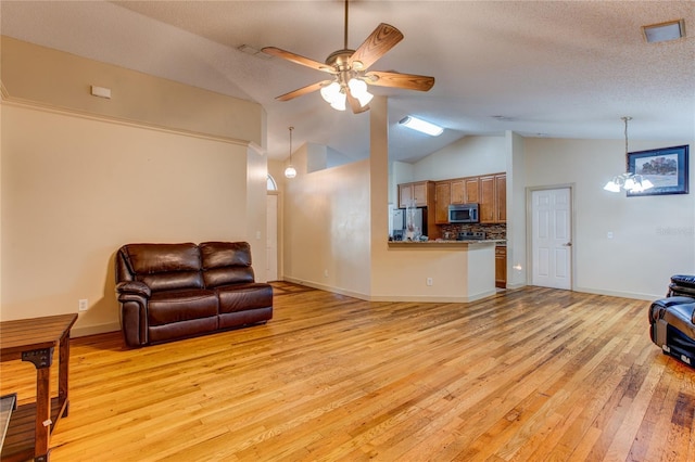 living room featuring a textured ceiling, ceiling fan with notable chandelier, light hardwood / wood-style flooring, and lofted ceiling