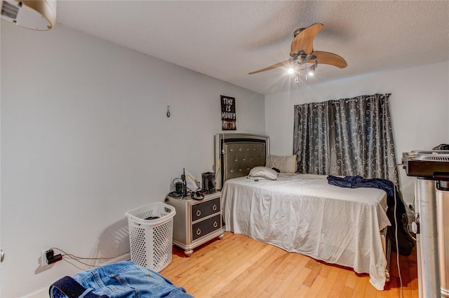 bedroom featuring ceiling fan, hardwood / wood-style floors, and a textured ceiling