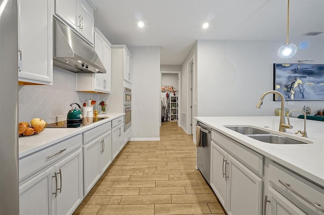 3359 Hanging Tide St, Winter Garden, FL 34787 - kitchen with stainless steel appliances, under cabinet range hood, white cabinetry, backsplash, and light wood finished floors