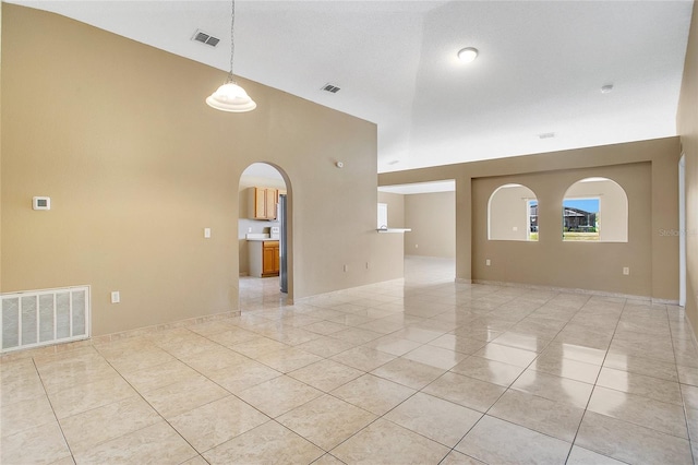 tiled spare room featuring high vaulted ceiling