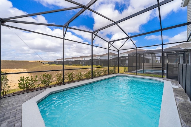 view of swimming pool featuring glass enclosure and a patio area