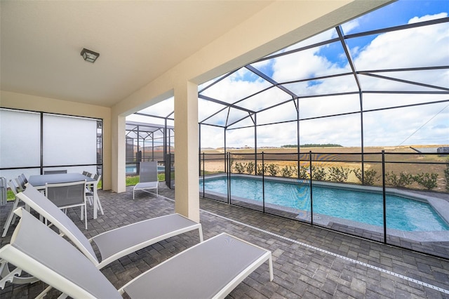 view of pool featuring a patio, a rural view, and glass enclosure