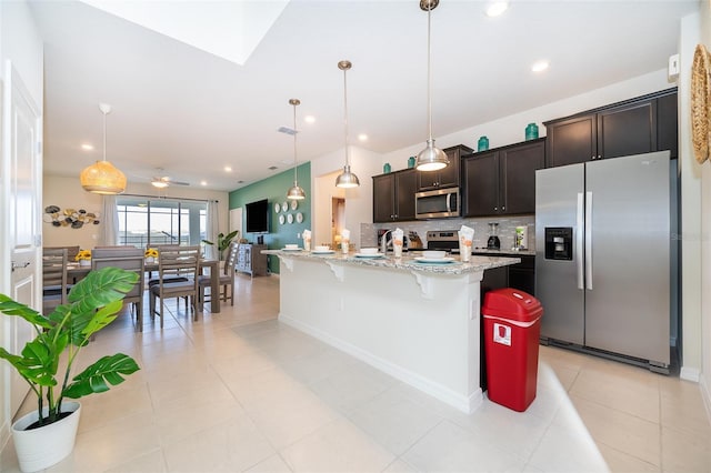 kitchen with pendant lighting, a breakfast bar, a center island with sink, tasteful backsplash, and stainless steel appliances