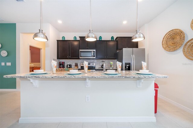 kitchen with pendant lighting, a kitchen island with sink, and appliances with stainless steel finishes