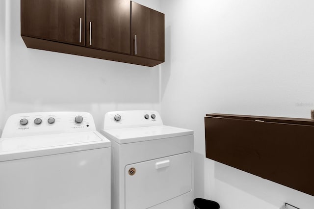 clothes washing area featuring cabinet space and independent washer and dryer