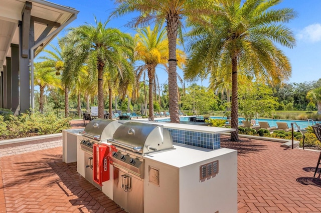 view of patio featuring exterior kitchen, a grill, and an outdoor pool