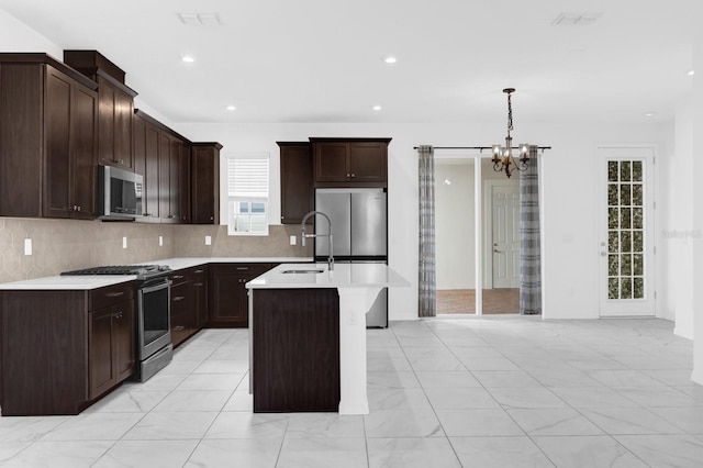 kitchen featuring decorative backsplash, an island with sink, stainless steel appliances, light countertops, and a sink