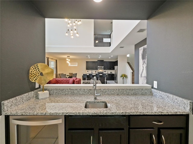 kitchen with light stone counters, an inviting chandelier, and sink