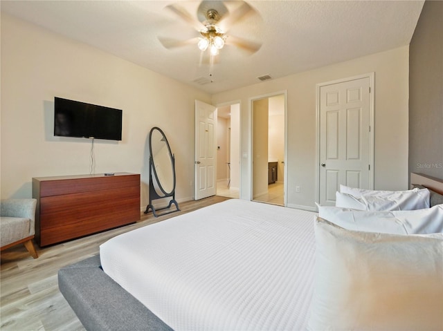 bedroom with light wood-type flooring, ensuite bathroom, and ceiling fan