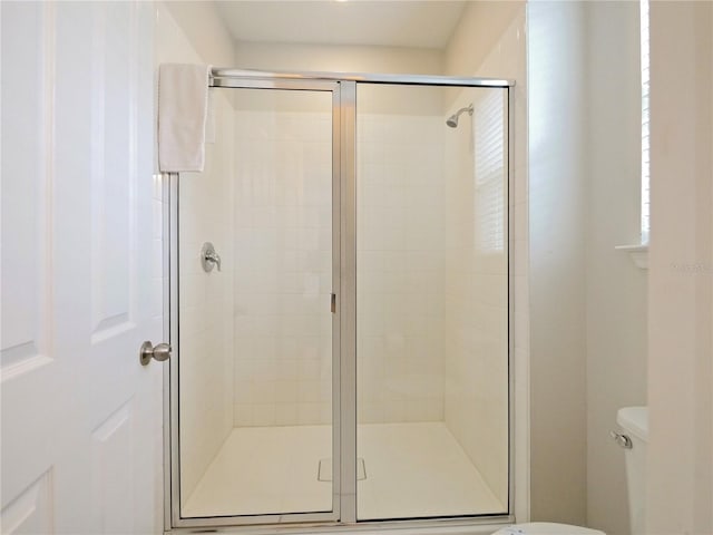 bathroom with toilet and a shower with door