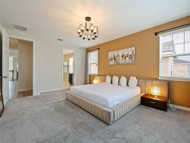 carpeted bedroom with ensuite bathroom and a chandelier