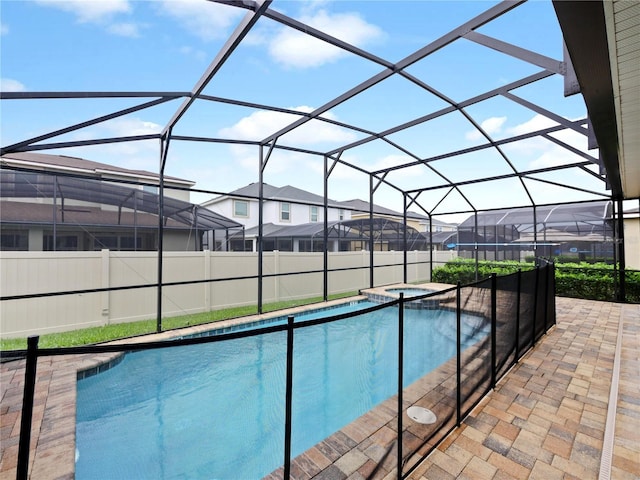 view of pool featuring glass enclosure, an in ground hot tub, and a patio