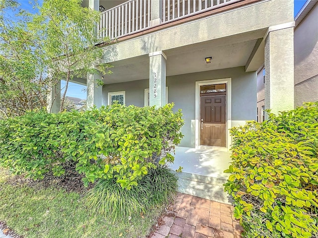 property entrance featuring a balcony and stucco siding