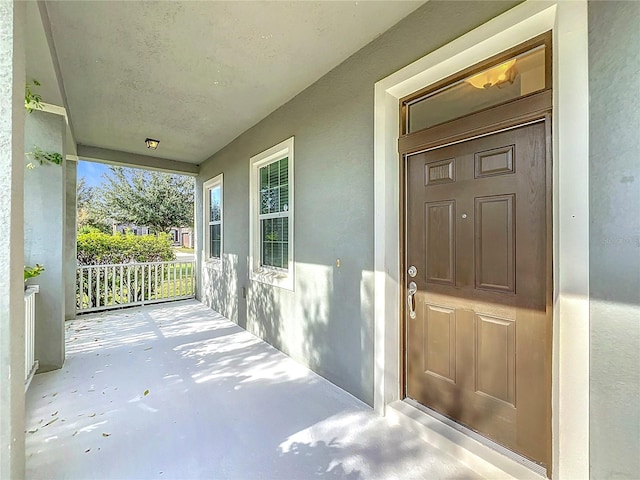 doorway to property with covered porch and stucco siding