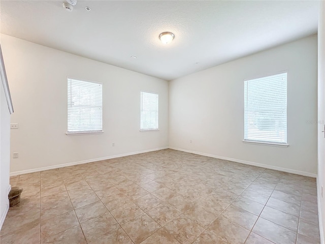 spare room featuring baseboards and light tile patterned floors