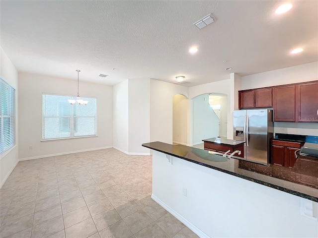 kitchen with visible vents, arched walkways, a peninsula, a textured ceiling, and stainless steel refrigerator with ice dispenser